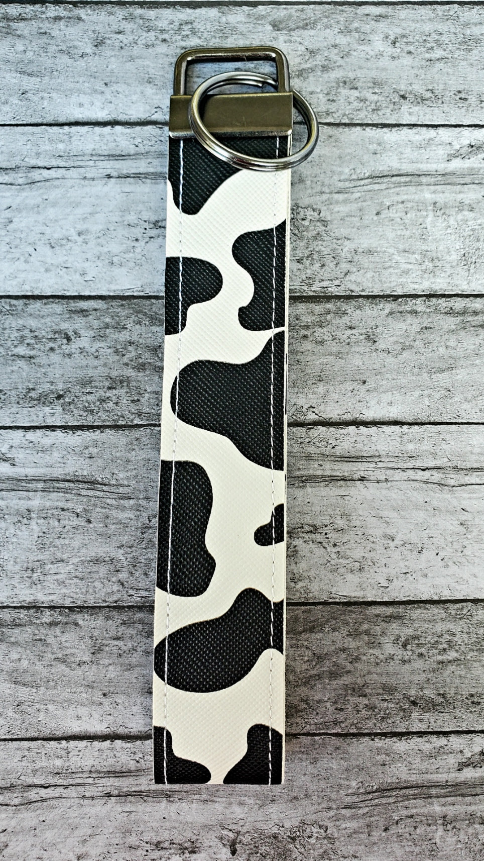 Cow print faux leather wristlet keychain with sewn edges.